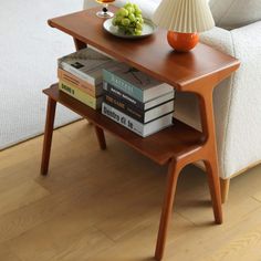 a coffee table with books and a bowl of fruit on it next to a couch