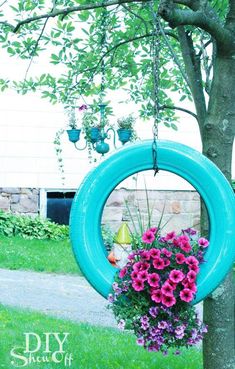 a blue tire hanging from a tree with flowers in it