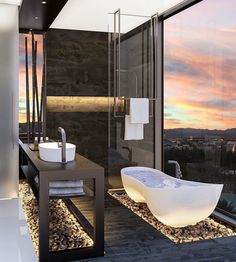 a modern bathroom with large windows overlooking the city at sunset or dawn, is pictured in this image