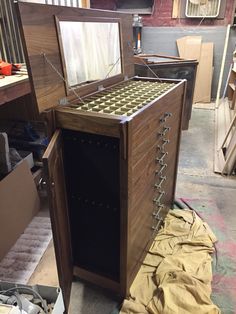 a wooden cabinet sitting on top of a floor next to a pile of boxes and other items