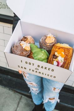 a person holding a box filled with baked goods and the words san francisco bakery crawl