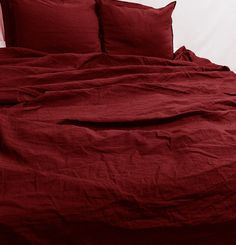 the bed is made with red linens and has two pillow cases on each side