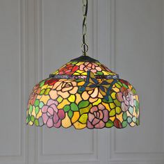 a stained glass lamp hanging from a chain in front of a white door with flowers on it