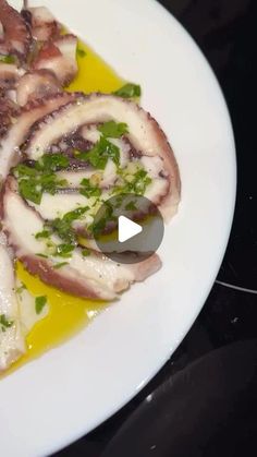 a white plate topped with octopus wrapped in sauce and garnished with parsley