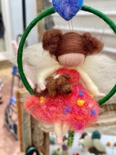 a small doll hanging from a green ring with a teddy bear on it's back