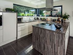 a modern kitchen with an island counter top and stainless steel appliances in the center, along with potted plants