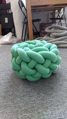 a large green object sitting on top of a carpeted floor next to a wooden table