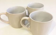 three white coffee mugs sitting next to each other