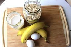 bananas, eggs and oatmeal sitting on a cutting board next to a jar