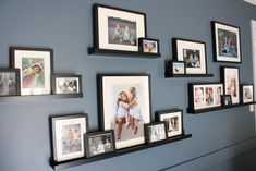 a wall with many pictures on it and some framed photos hanging up against the wall