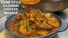 a blue bowl filled with chicken masala sitting on top of a wooden cutting board