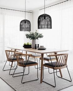 a dining room table with four chairs and a plant in the vase on top of it