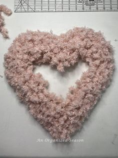 a heart made out of pink yarn next to a ruler