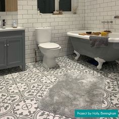 a bathroom with a toilet, sink, and bathtub in grey and white tile