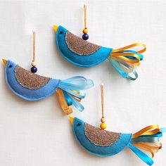 three blue and yellow bird ornaments hanging from strings