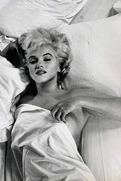 an old black and white photo of a woman laying in bed