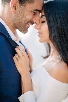 a man and woman standing next to each other with their arms around each other, smiling