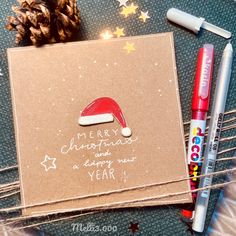 a christmas card with a santa hat on it next to some markers and crayons