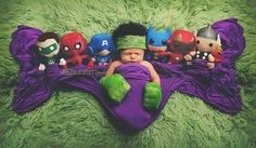 a baby is laying on a blanket with stuffed animals around him and wearing headgear