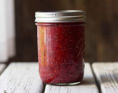 a jar filled with red liquid sitting on top of a wooden table