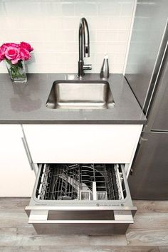 a stainless steel dishwasher with the door open and a pink flower in it