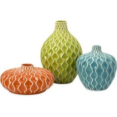 three different colored vases sitting next to each other on a white surface with wavy lines