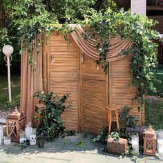 an outdoor wedding ceremony with wooden doors and greenery on the wall, surrounded by candles