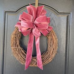 a wreath with a pink bow hanging on the front door