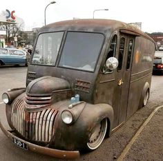 an old, rusty truck is parked in a parking lot with other cars behind it