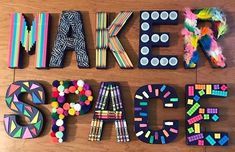 the word fake space spelled out in colorful letters on a wooden floor with pom poms