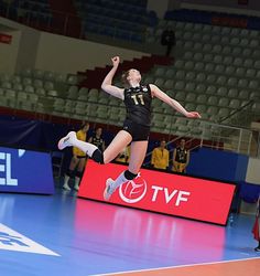 a woman jumping in the air to hit a volleyball