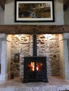 a wood burning stove sitting inside of a stone wall next to a painting on the wall