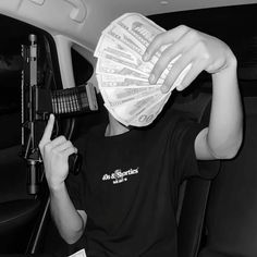 a person sitting in a car with money on their head and hair dryer over his face