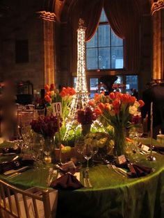 the table is set with flowers and place settings in front of the eiffel tower