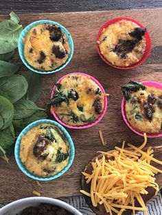 several small cups filled with food sitting on top of a wooden table next to greens