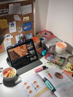 an open laptop computer sitting on top of a desk covered in papers and other items