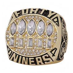 a gold ring with white and clear stones on the front, surrounded by black lettering