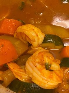 a bowl full of soup with shrimp and carrots