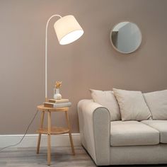 a living room with a couch, table lamp and round mirror on the wall above it