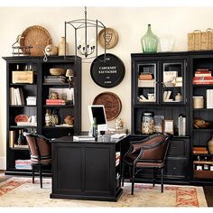 a home office with black bookcases and leather chairs