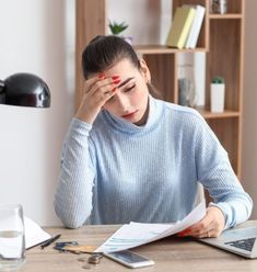 a woman sitting at a desk holding her head