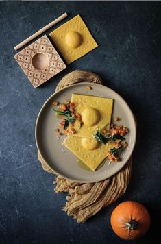 two pieces of food sitting on top of a white plate next to an orange pumpkin