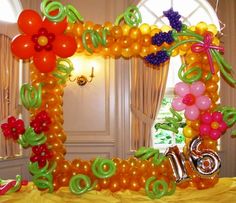 a balloon arch decorated with flowers and balloons