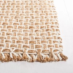 an area rug with white and brown woven squares on the top, in front of a wooden floor