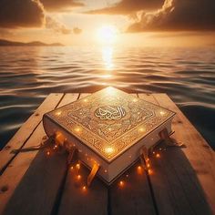 an illuminated book sitting on top of a wooden dock in the middle of the ocean