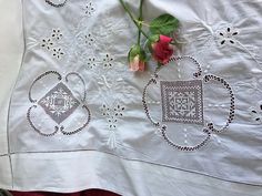 a white table cloth with two roses on it and a pair of scissors next to it