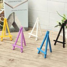 three small wooden easels sitting on top of a wooden table next to a vase with flowers