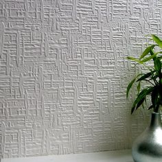 a potted plant sitting on top of a white shelf next to a wall paper