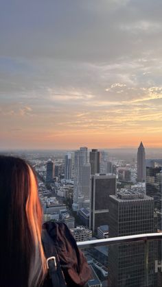 a woman standing on top of a tall building looking at the city below with buildings in the background