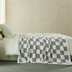 a bed with a checkered blanket on top of it next to a white chair